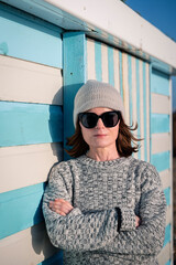 woman standing in the winter sun outdoors by a beach hut