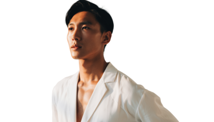 Stylish young Asian man in a white jacket looking away thoughtfully in a studio portrait
