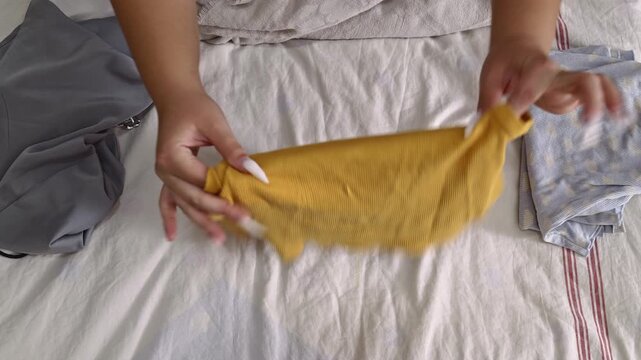 Detailed close-up of a woman's hands meticulously folding various clothing items, demonstrating efficient wardrobe organization. This captures the practical process of tidying for a decluttered home.