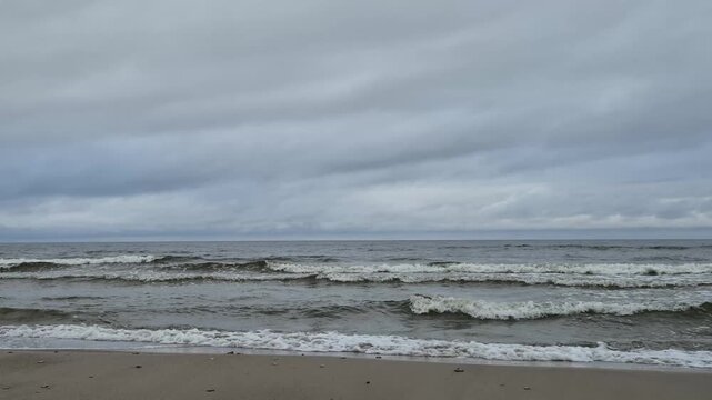 Calm sea waves breaking near the shoreline beneath a cloudy sky. Natural ocean sounds, peaceful coastal atmosphere, minimalist seascape. 4K relaxing nature video.