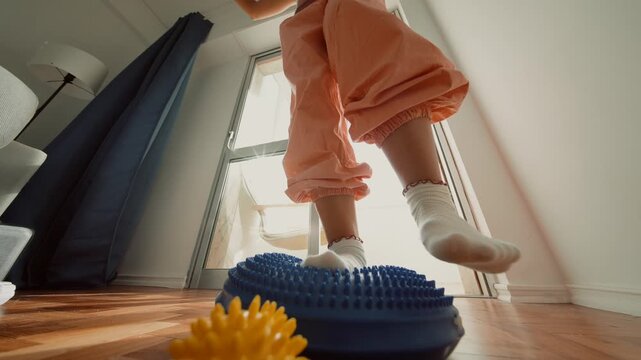 closeup socked foot stepping on balance cushion and spiky ball