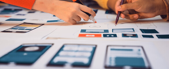 Creative hands engaged in brainstorming during a mobile app design session, sketching interface...