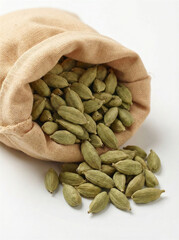 Green cardamom pods spilling from a rustic cloth bag on a white background