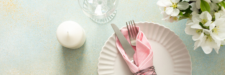 A beautiful spring table setting showcases soft pastel napkins neatly arranged on a plate alongside a candle and fresh flowers, creating an inviting dining atmosphere, banner