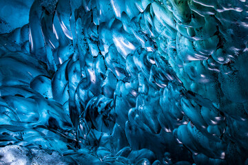 Abstract close-up of deep blue scalloped ice ripples inside an Icelandic glacier cave