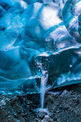 Small waterfall flowing from the blue ice ceiling of Crystal Cave near Jokulsarlon