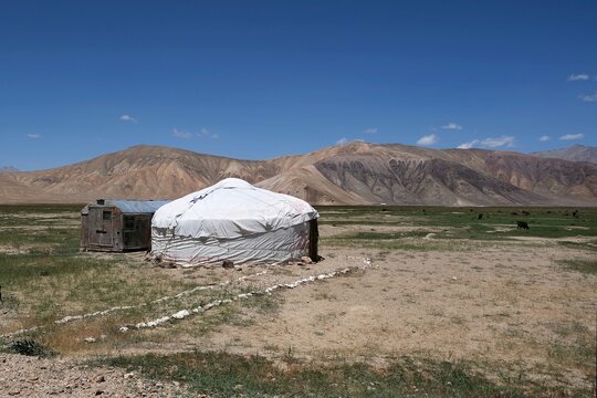 View of high-altitude Bulunkul village with white yurt, surroundings with mountain background, near Bulunkul and Yashilkul lakes, Pamir Highway in Gorno-Badakshan, Tajikistan