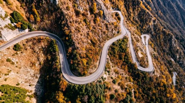 Curving mountain road winds along steep hillside covered in autumn colors offering dramatic scenic drive and adventurous travel route