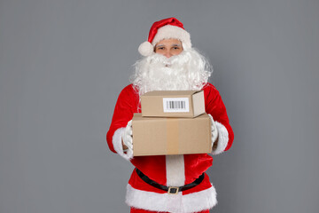 Santa Claus with parcels on grey background
