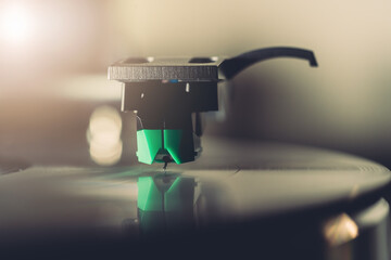 Stylus needle playing vinyl record on turntable close up. Retro analog music equipment with soft ambient lighting. Nostalgia, vintage audio, and timeless sound experience concept.