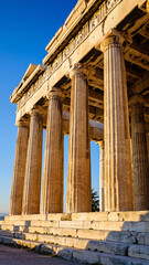 Obraz premium Ancient Greek temple with tall columns under a bright blue sky.
