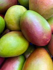 A pile of fresh ripe, juicy mangoes in the market. Food and fruit background. Top view, close-up. Fruits for sale in the supermarket.
