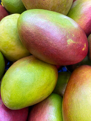 A pile of fresh ripe, juicy mangoes in the market. Food and fruit background. Top view, close-up. Fruits for sale in the supermarket.