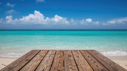 A wooden dock extending toward the turquoise sea under a blue sky with clouds.