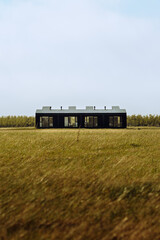 Contemporary black minimalist house standing alone in an open field in Iceland. Architecture blending modern design with wild Nordic landscape