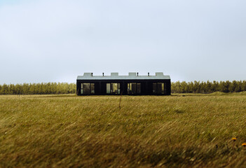 Contemporary black minimalist house standing alone in an open field in Iceland. Architecture blending modern design with wild Nordic landscape