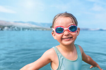 Smiling child wearing goggles in blue sea