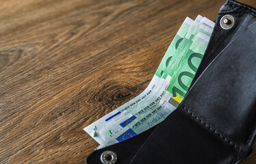 Euro banknotes in wallet on wooden table