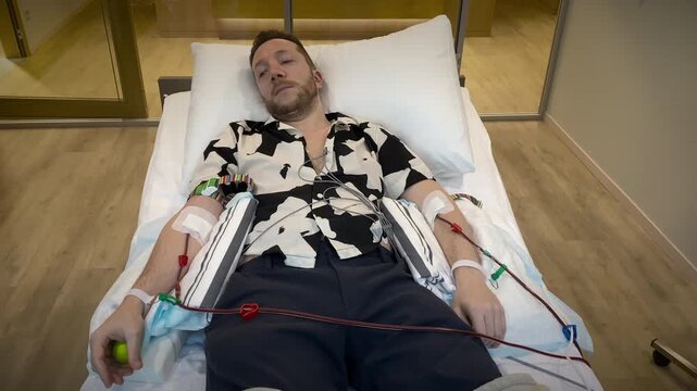 Reclining Individual Connected To Apheresis Equipment Receiving Blood Plasma Donation In Clinical Setting