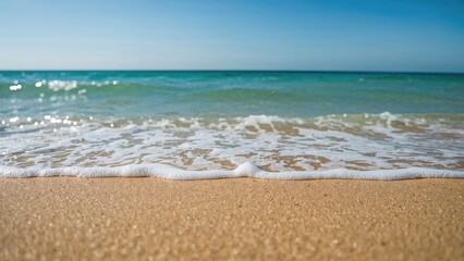 Fototapeta premium A calm beach scene with waves gently reaching the sandy shore.