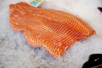 Freshly cut salmon fillet resting on ice at a bustling market