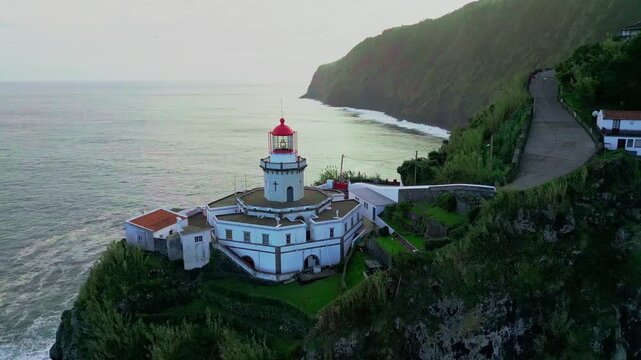 Scenic view of Ponta do Arnel Lighthouse (Farol do Arnel) perched on steep cliffs in Nordeste, Sao Miguel, Azores.