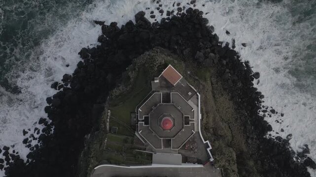 Scenic view of Ponta do Arnel Lighthouse (Farol do Arnel) perched on steep cliffs in Nordeste, Sao Miguel, Azores.