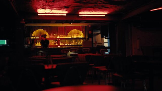 Empty bar interior with warm lighting and bottles at night