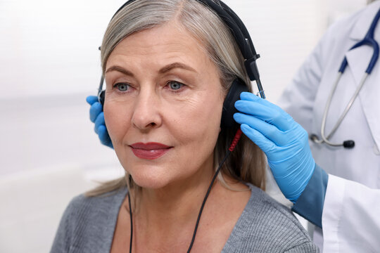 Hearing test. Doctor adjusting patient's audiometric headphones in clinic, closeup