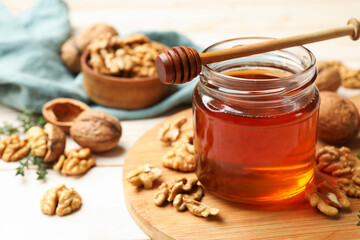 Sweet honey with walnuts and dipper on wooden table, closeup