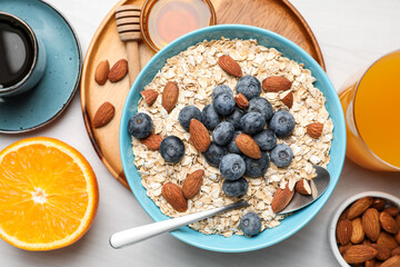 Dry oat flakes, nuts and blueberries served on grey wooden table for breakfast, flat lay