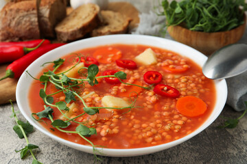 Delicious lentil soup with vegetables served on grey table, closeup