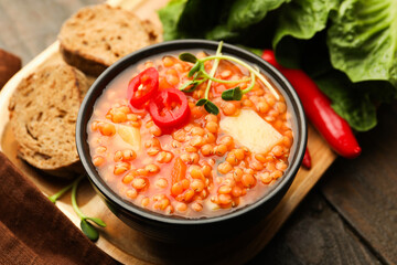 Delicious lentil soup with vegetables served on wooden table, closeup