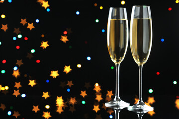 Flute glasses with sparkling wine on black background, space for text. Merry Christmas and Happy New Year