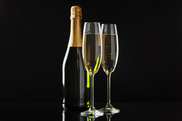 Flute glasses with sparkling wine and bottle on black background. Merry Christmas and Happy New Year