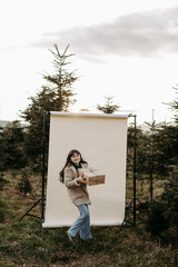 M&auml;dchen, 11, mit Weihnachtsgeschenk vor beigem Studiohintergrund in der Natur