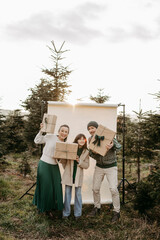 Familie steht in der Natur vor einem beigen Studiohintergrund mit Geschenken in der Hand