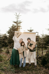 Familie steht in der Natur vor einem beigen Studiohintergrund mit Geschenken in der Hand