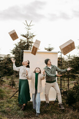 Familie steht in der Natur vor einem beigen Studiohintergrund und wirft Geschenke in die Luft