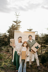 Familie steht in der Natur vor einem beigen Studiohintergrund und wirft Geschenke in die Luft
