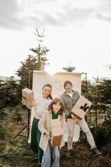 Familie steht in der Natur vor einem beigen Studiohintergrund und wirft Geschenke in die Luft