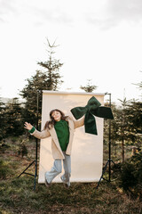 M&auml;dchen mit gr&uuml;ner Masche in der Hand steht vor beigem Studiohintergrund in der Natur