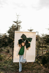 M&auml;dchen mit gr&uuml;ner Masche in der Hand steht vor beigem Studiohintergrund in der Natur