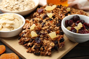 Tasty granola bars with dried fruits and nuts on black wooden table, closeup