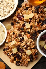 Tasty granola bars with dried fruits and nuts on black wooden table, flat lay