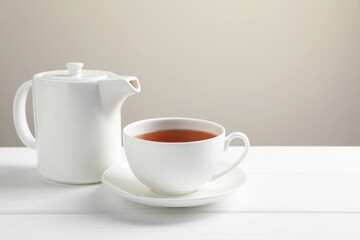 Hot tea in cup and teapot on white wooden table. Space for text