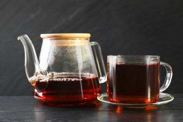 Hot tea in cup and teapot on black wooden table
