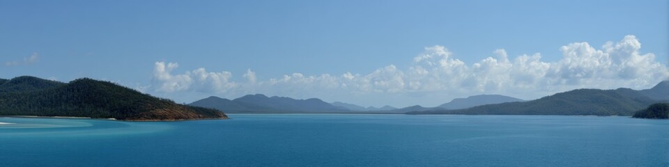 Fototapeta premium Serene panorama of turquoise sea and verdant islands under cloudy blue sky