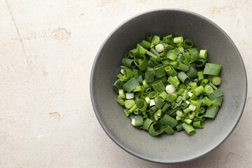 Bowl with cut green onions on light grey table, top view. Space for text