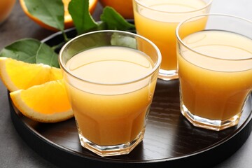 Fresh orange juice, fruits and leaves on grey table, closeup